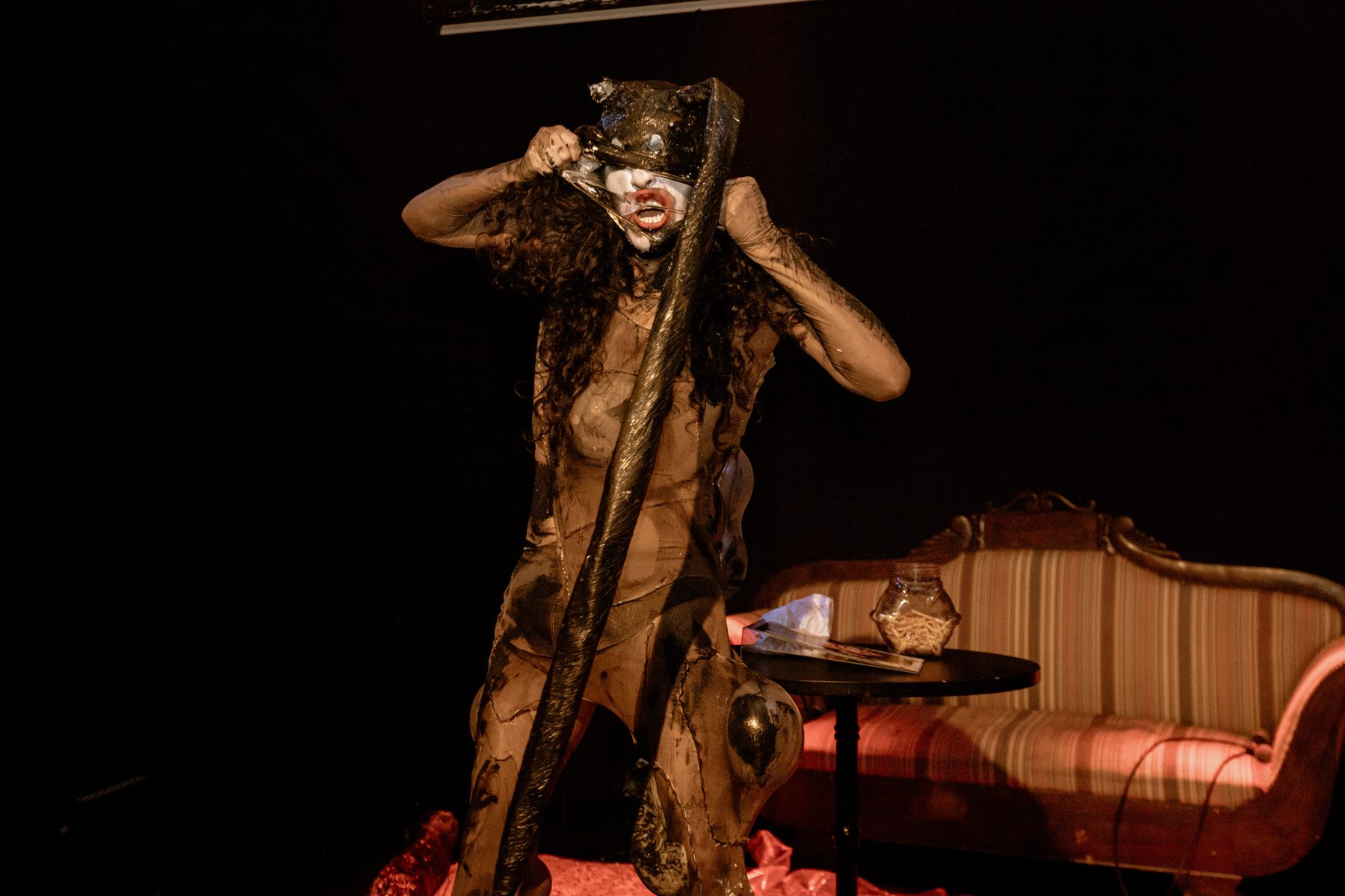 wiqi pulling on a latex mask during a theatrical performance