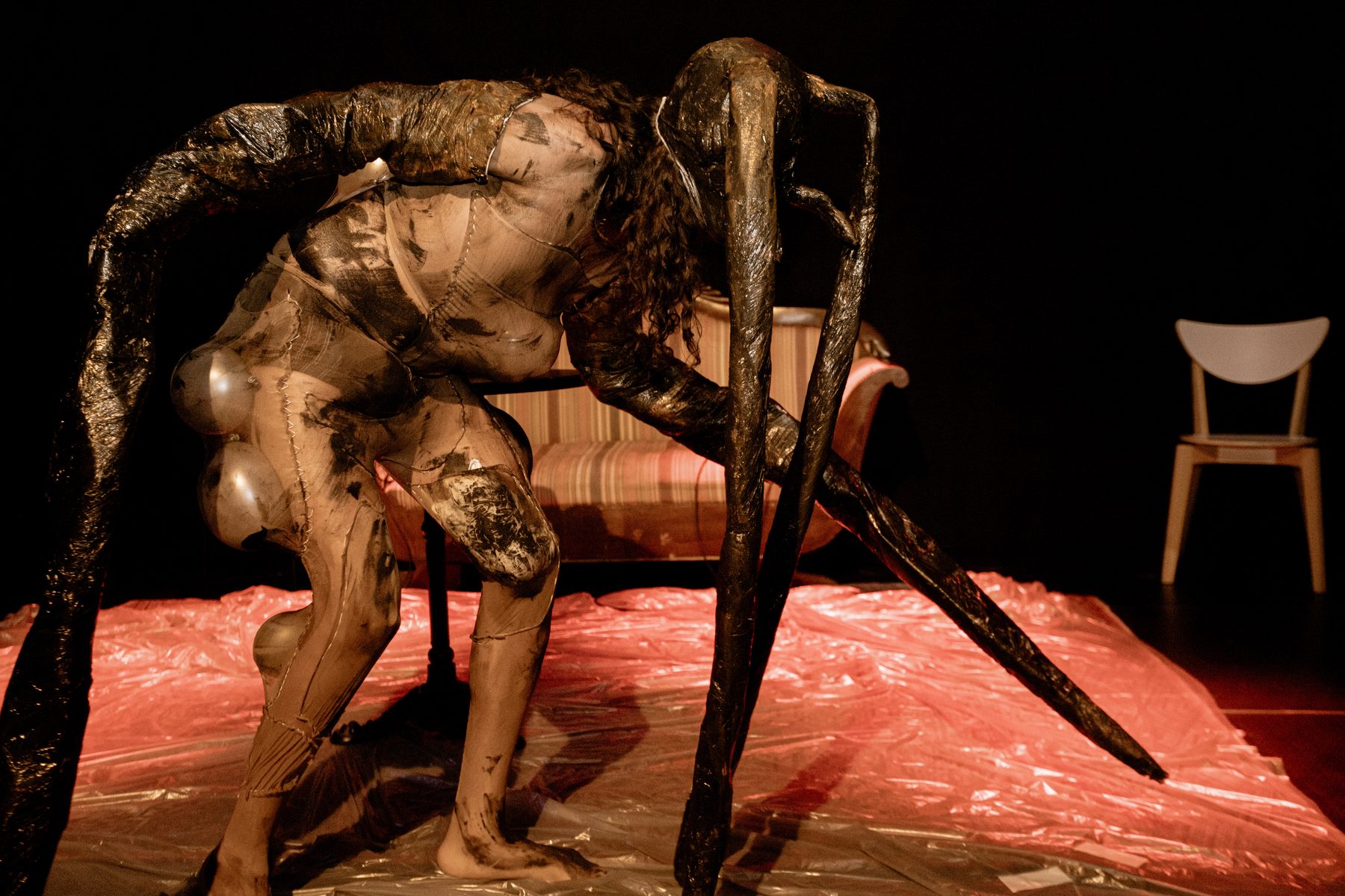 wiqi in an insect-like latex creature costume, side view